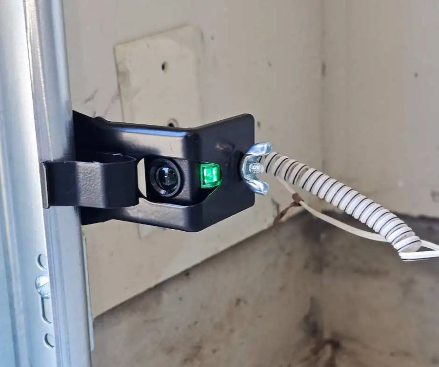 Garage door photo-eye safety sensor mounted near the floor