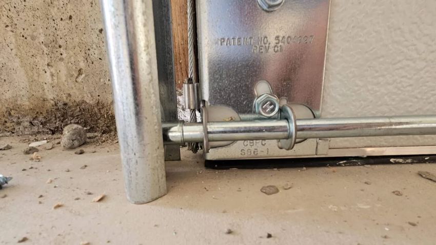Bottom bracket with cable attached at the base of a garage door